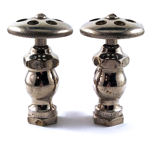 Two nickel-plated angle stops, seen from the back. They have wide, flat knobs with decorative holes in them, and are stamped "Standard" on the base of each one. They have a fair amount of surface wear.