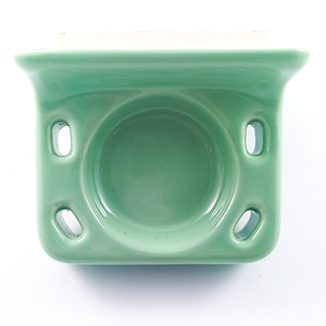 The toothbrush holder, which is a rounded rectangle with four holes for toothbrushes, one in each corner. In the center is a round divot, typically used for holding a cup