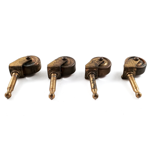 Four antique grip-neck stem casters made fully of brass, with the photo showing the tops of the casters. There is significant surface wear on the metal.