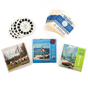 Lot A - Travel. Pictured are three sets - Sweden, Islands of Romance, and Seattle Center - as well as one stack of sleeved reels and four loose reels. At the top of each stack are "Dells of the Wisconsin River II" and "Duluth and North Shore Drive"