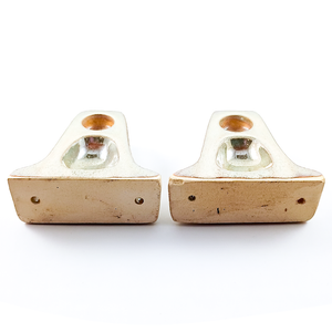 A photo focusing primarily on the undersides of the pieces, showing that they are a warm off-white clay with some tool marks as well as visible screw holes. The angle of the photo also makes the silver sheen on the glazed portions very bright.
