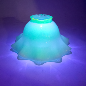 The lamp shade upside down again, under UV light and fluorescing bright green. The light from the UV lamp is being refracted through the shade in an interesting pattern.