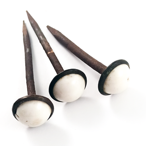 Three rusted iron nails with white porcelain domed heads