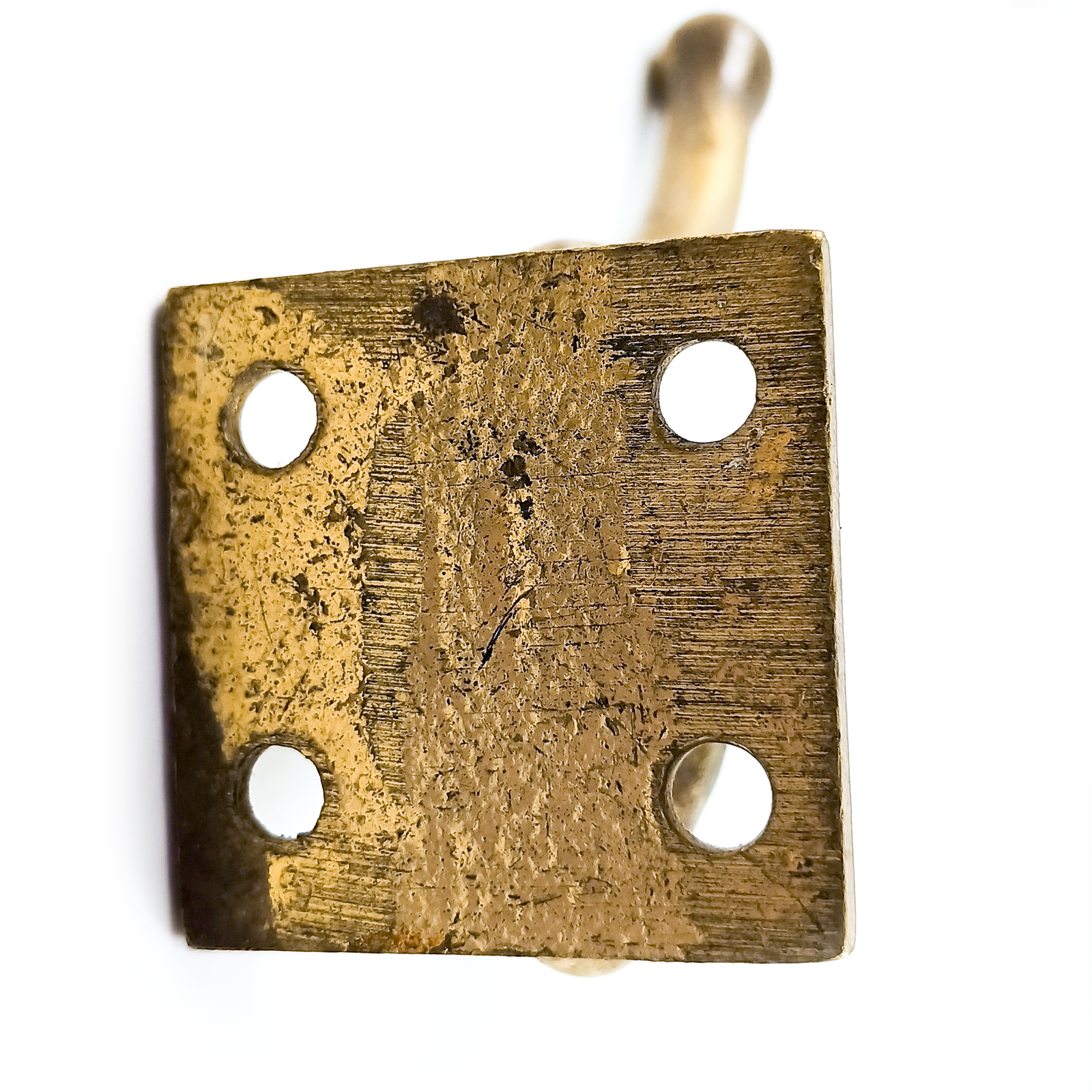 A brass or brass-plated coat hook with two prongs. There is a fair amount of wear on the surface.