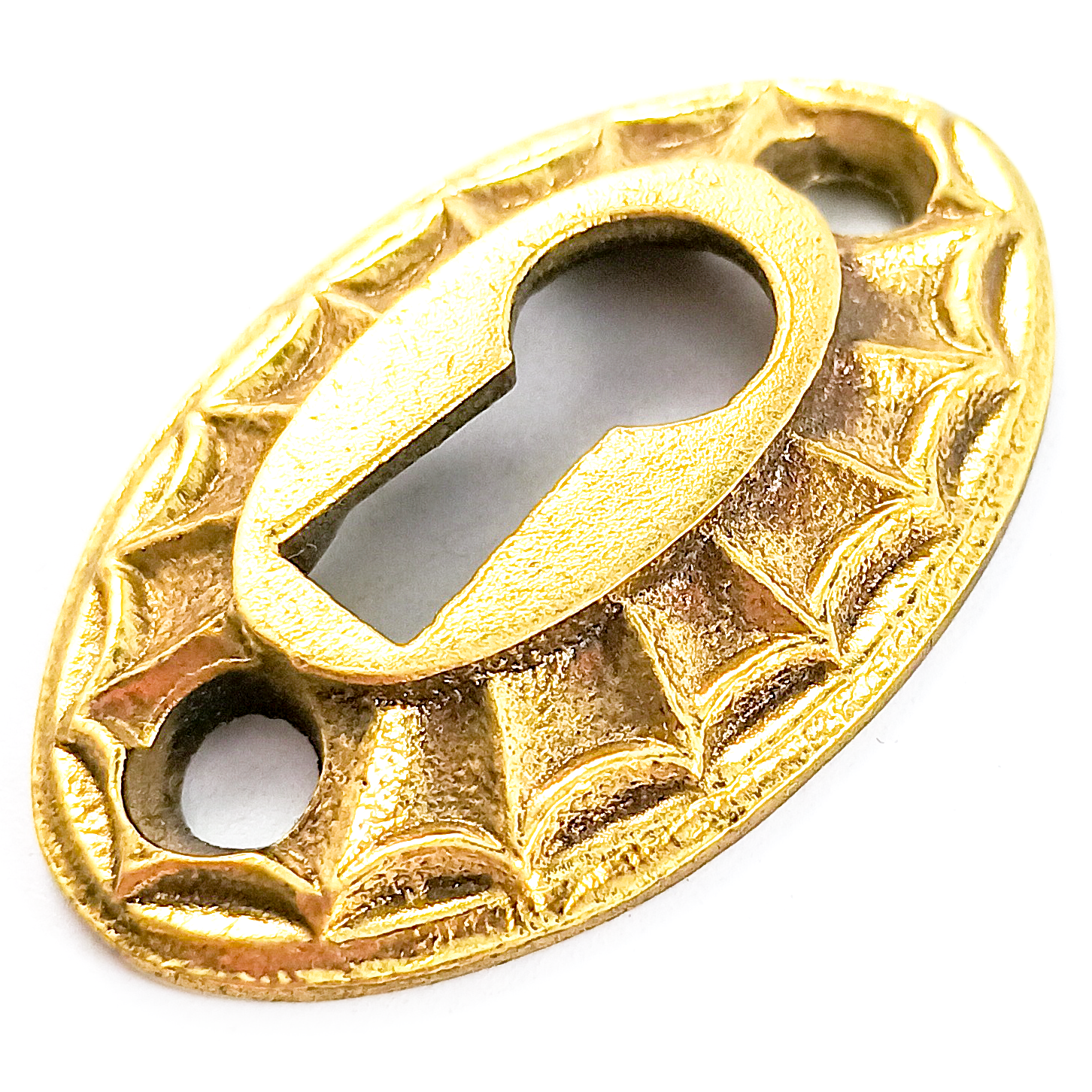 A vintage brass oval keyhole escutcheon, with a raised ray pattern resembling a sunburst or spiderweb