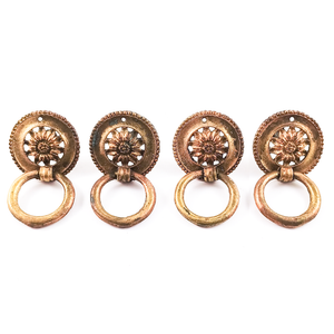 Four vintage brass ring pulls with sunflowers in the middle and beaded edges, with the rings flipped, showing that the backs of the rings and the place where they rest on the rosettes are both smooth and undecorated.