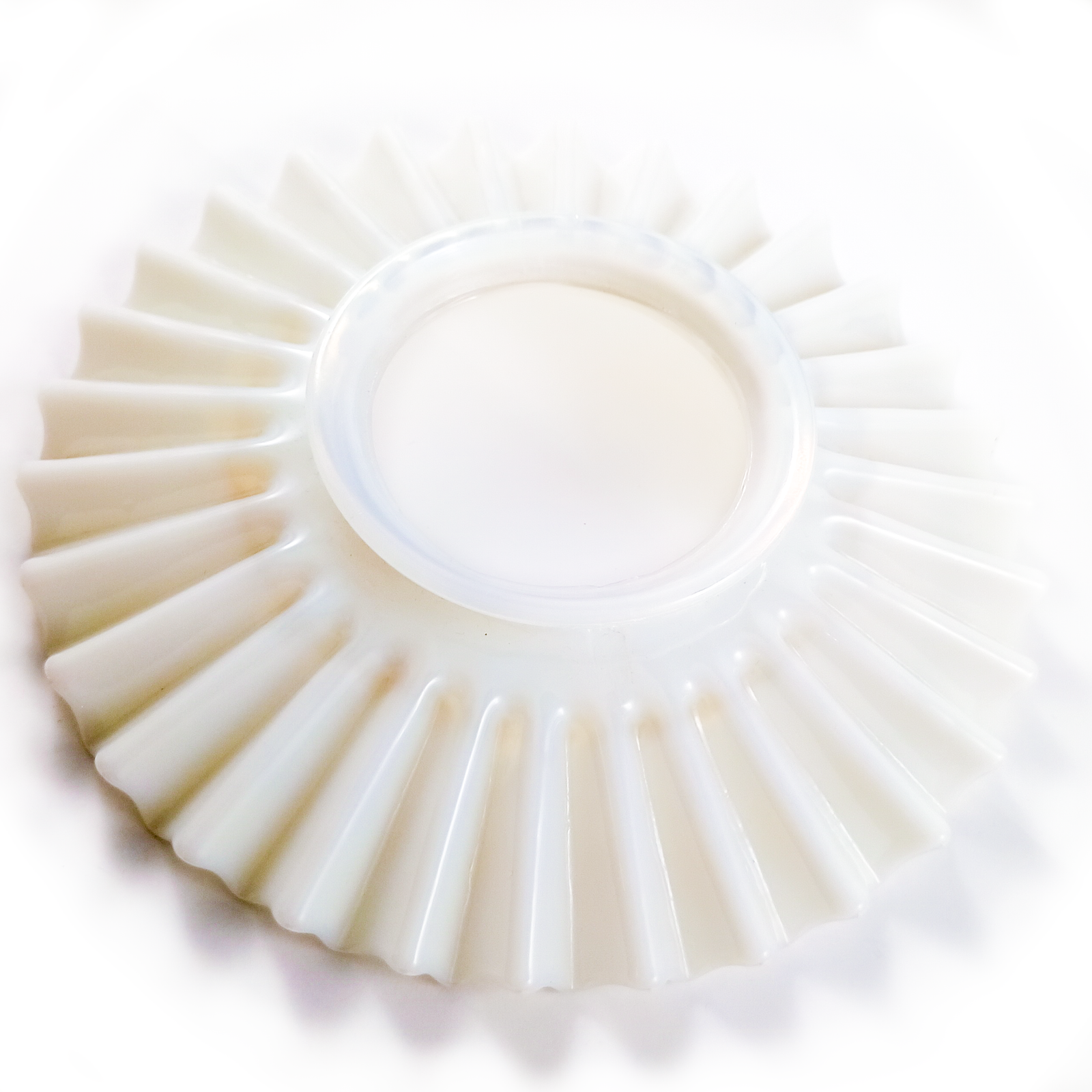 A round, ruffled lamp shade made of white, opalescent glass, photographed on a white background to show the warm opalescence