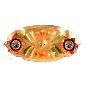 A photo of a vintage gold-tone ceiling light fixture with two sockets, each of which is housed in a red flower shape. There are red and green scrolling decorations in the middle of the fixture.