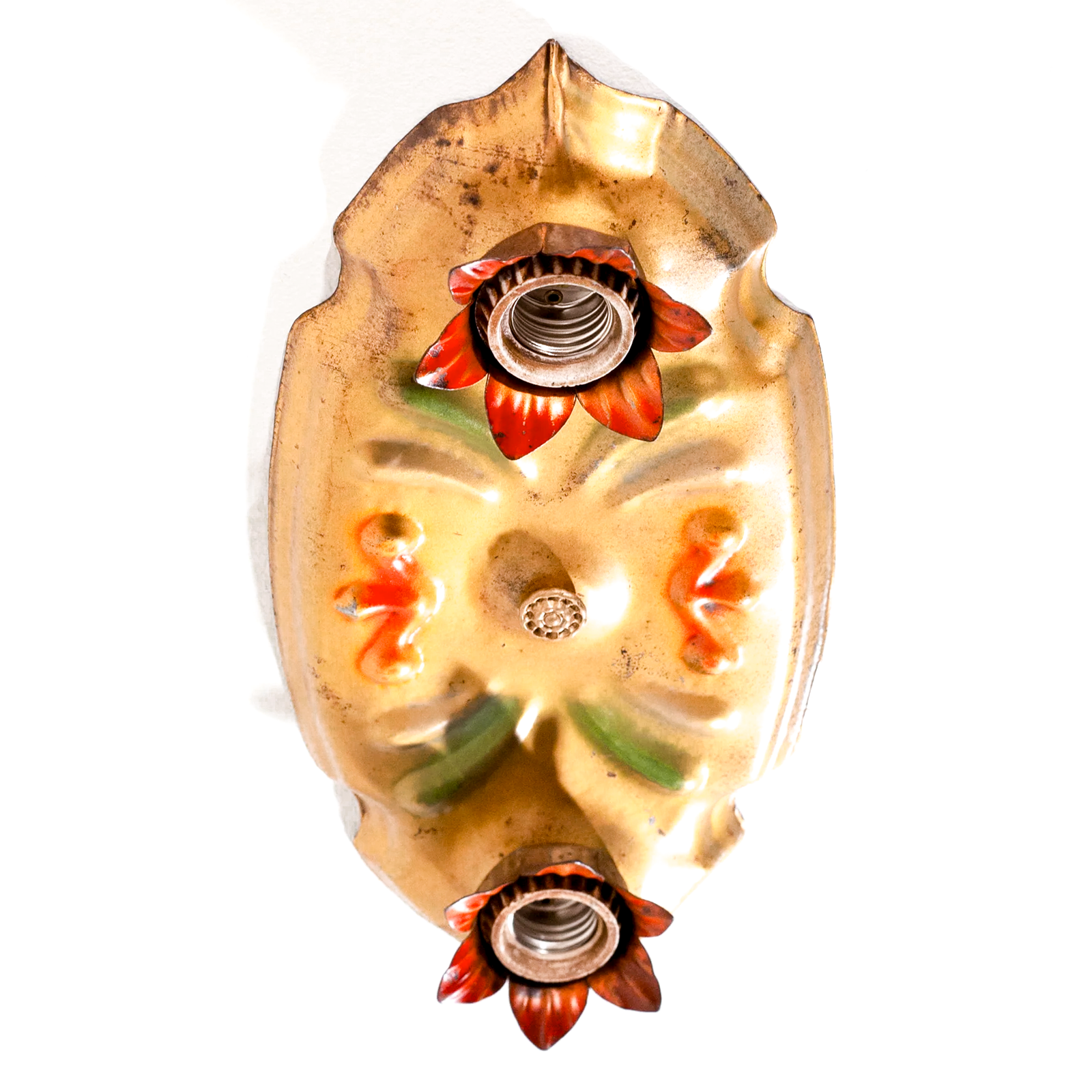 A photo of a vintage gold-tone ceiling light fixture with two sockets, each of which is housed in a red flower shape. There are red and green scrolling decorations in the middle of the fixture.