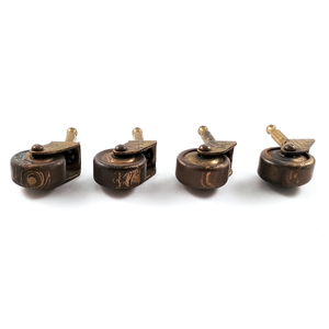 A side and underside view of four antique brass casters