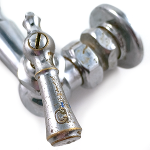 A close-up of a chrome-plated brass lever handle on an antique farmhouse faucet, labeled "C" for cold, which has a fair amount of brass showing through the chrome plating