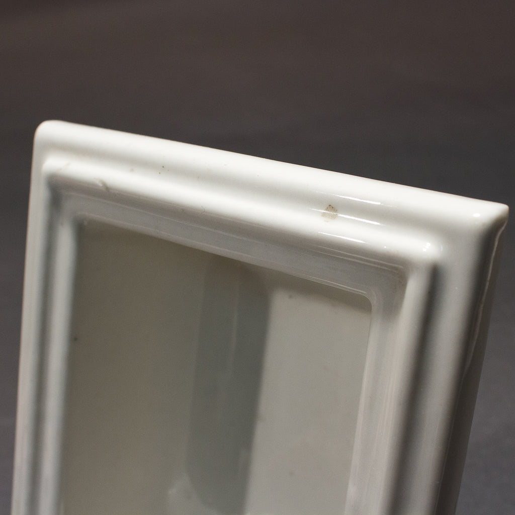 this is an up close picture showing a small spot or stain on an antique white porcelain soap holder