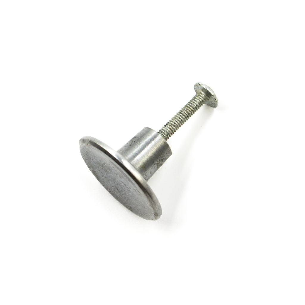 this is a side view of a vintage mid century brushed nickel concave cabinet or drawer pull knob showing how the screw attaches