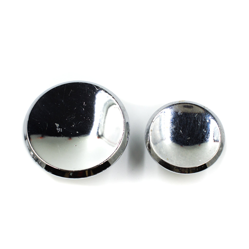 this is side angle view of a large and small vintage mid century chrome colored cabinet or drawer pull knobs
