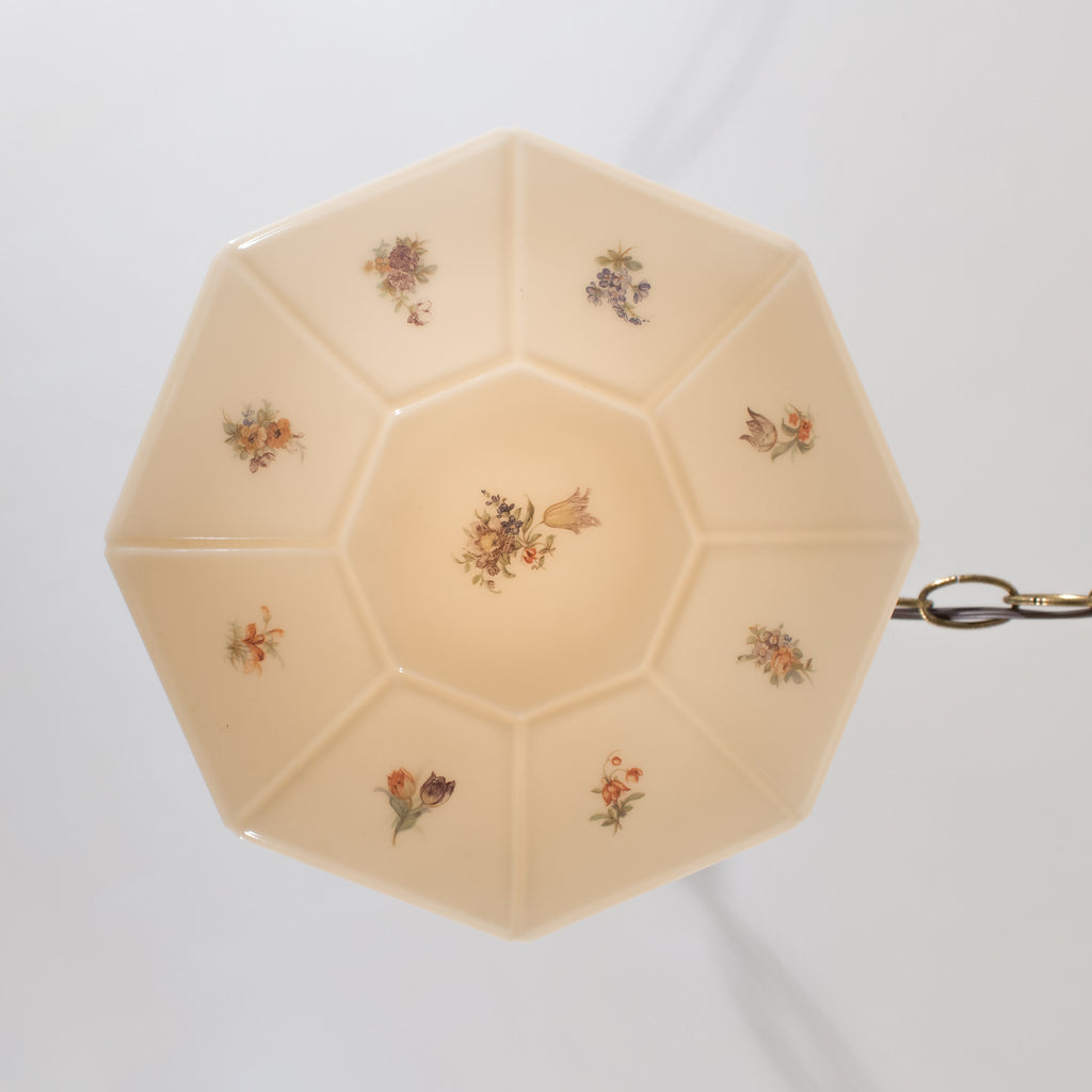 this is a picture of the bottom of a vintage art deco glass shade in a cream color with a floral pattern 